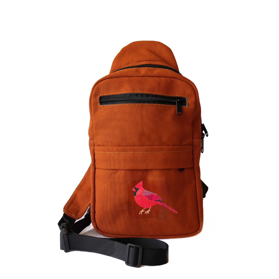 Cardinal Umoja embroidered canvas unisex sling bag in rust